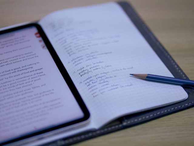 An open notebook with handwritten planning notes next to a pencil and a phone.